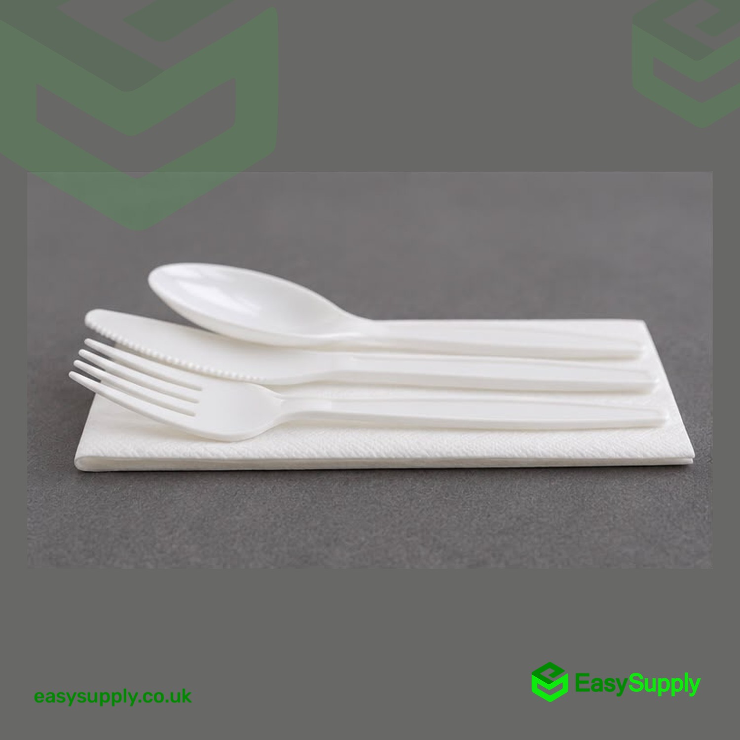 White plastic fork, knife and spoon laid on a folded paper napkin, side view